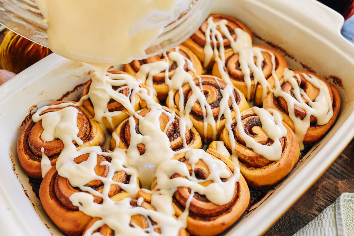drizzling icing over cinnamon rolls