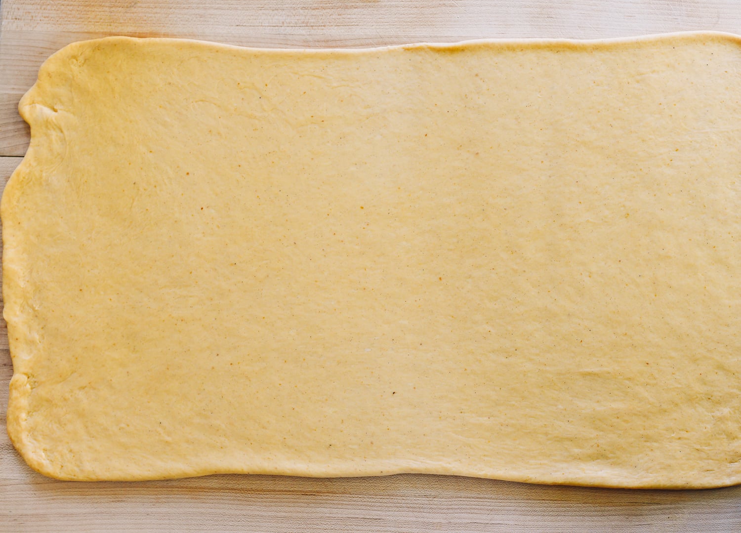 pumpkin cinnamon roll dough rolled out into large rectangle