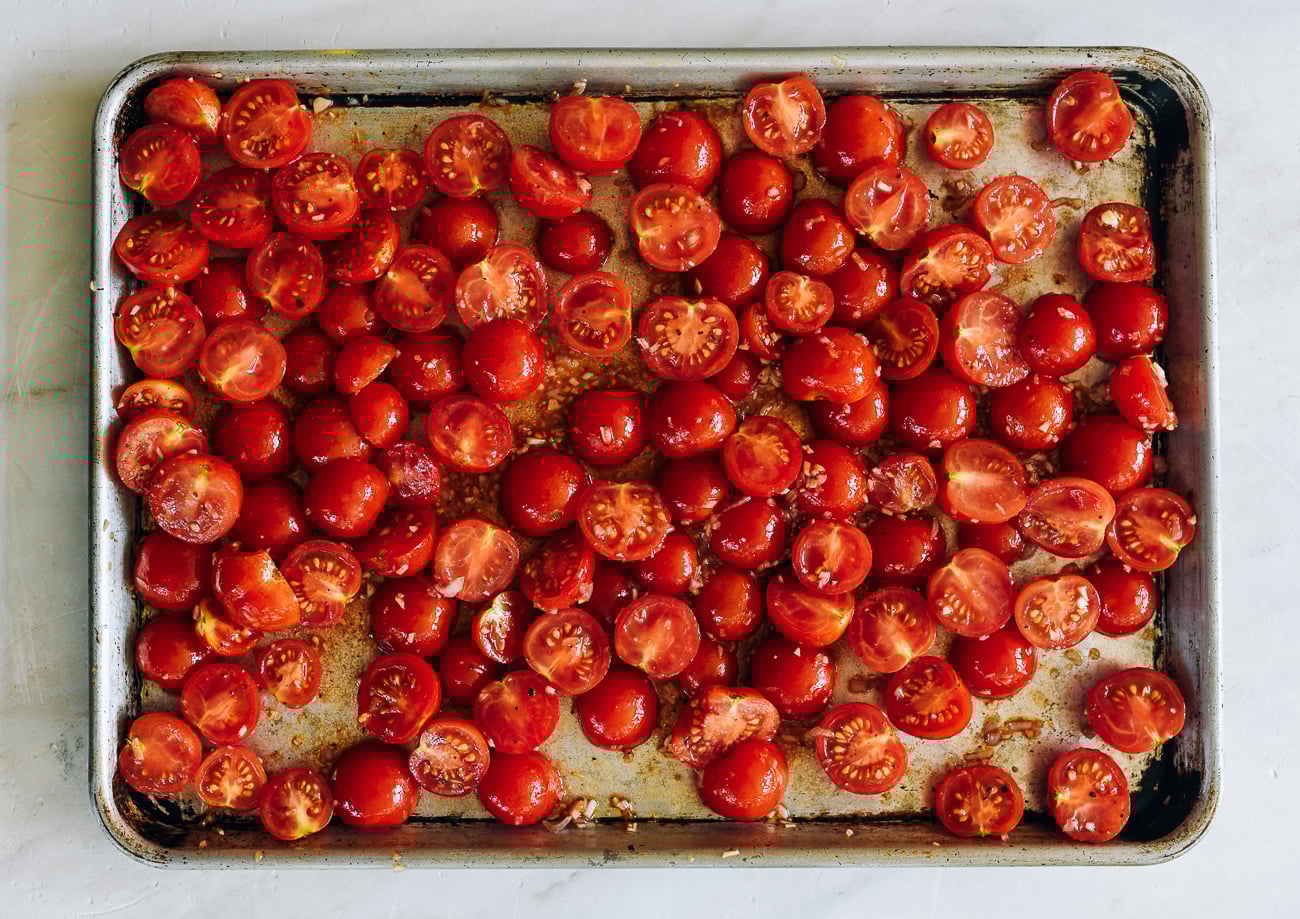 seasoned halved cherry tomatoes on sheet pan for roasting