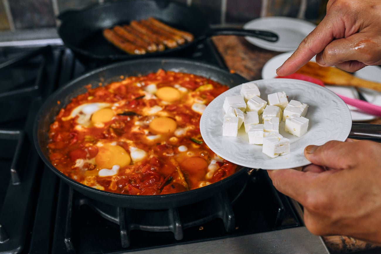 adding cubed feta cheese to shakshuka