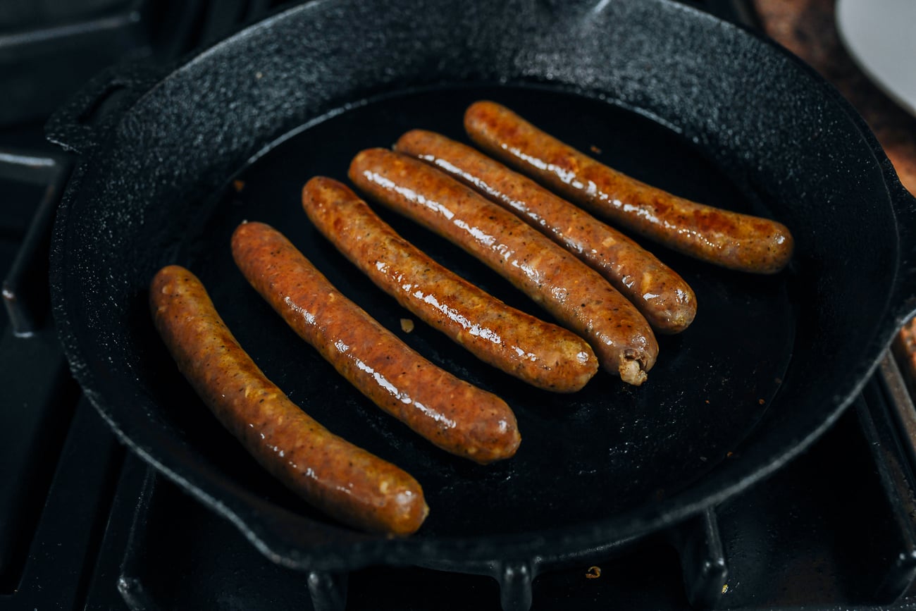 merguez sausages cooking in cast iron skillet