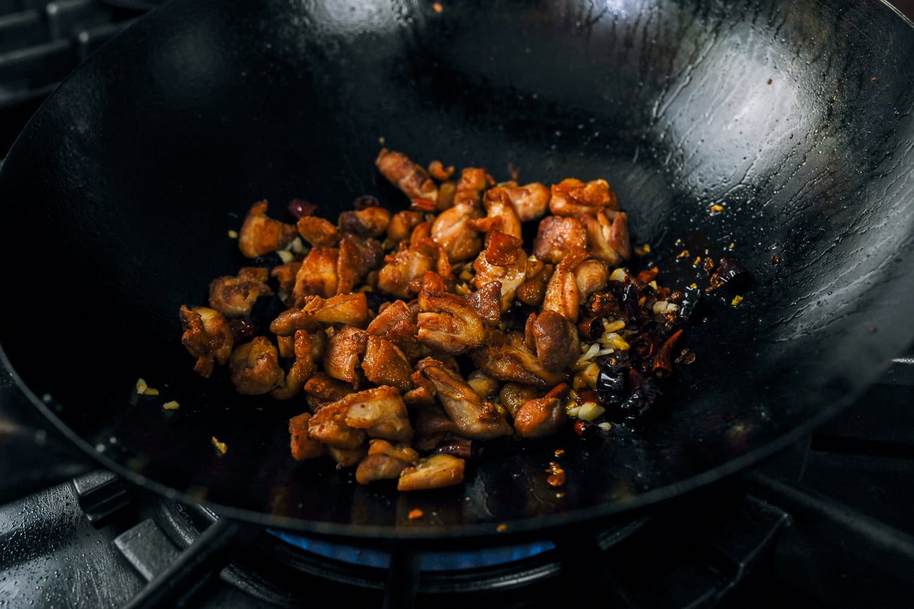 adding chicken back to wok with chilies