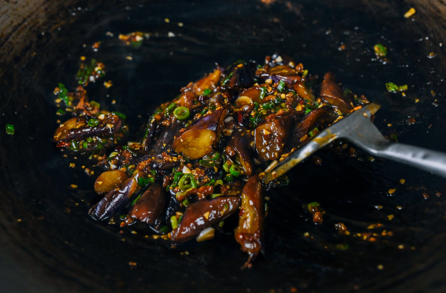 stirring eggplant with garlic sauce in wok
