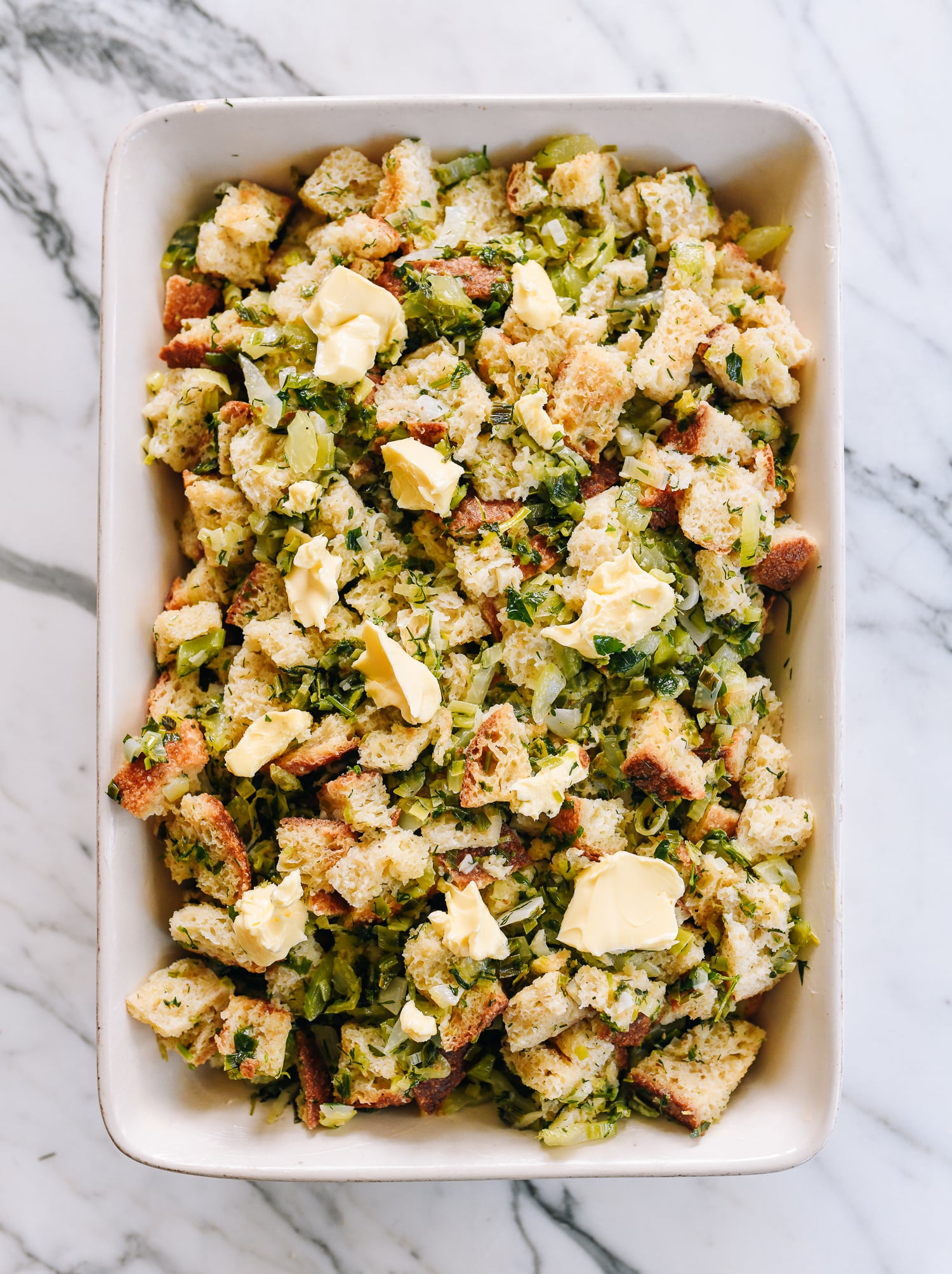stuffing mixture in baking dish with butter on top, before cooking
