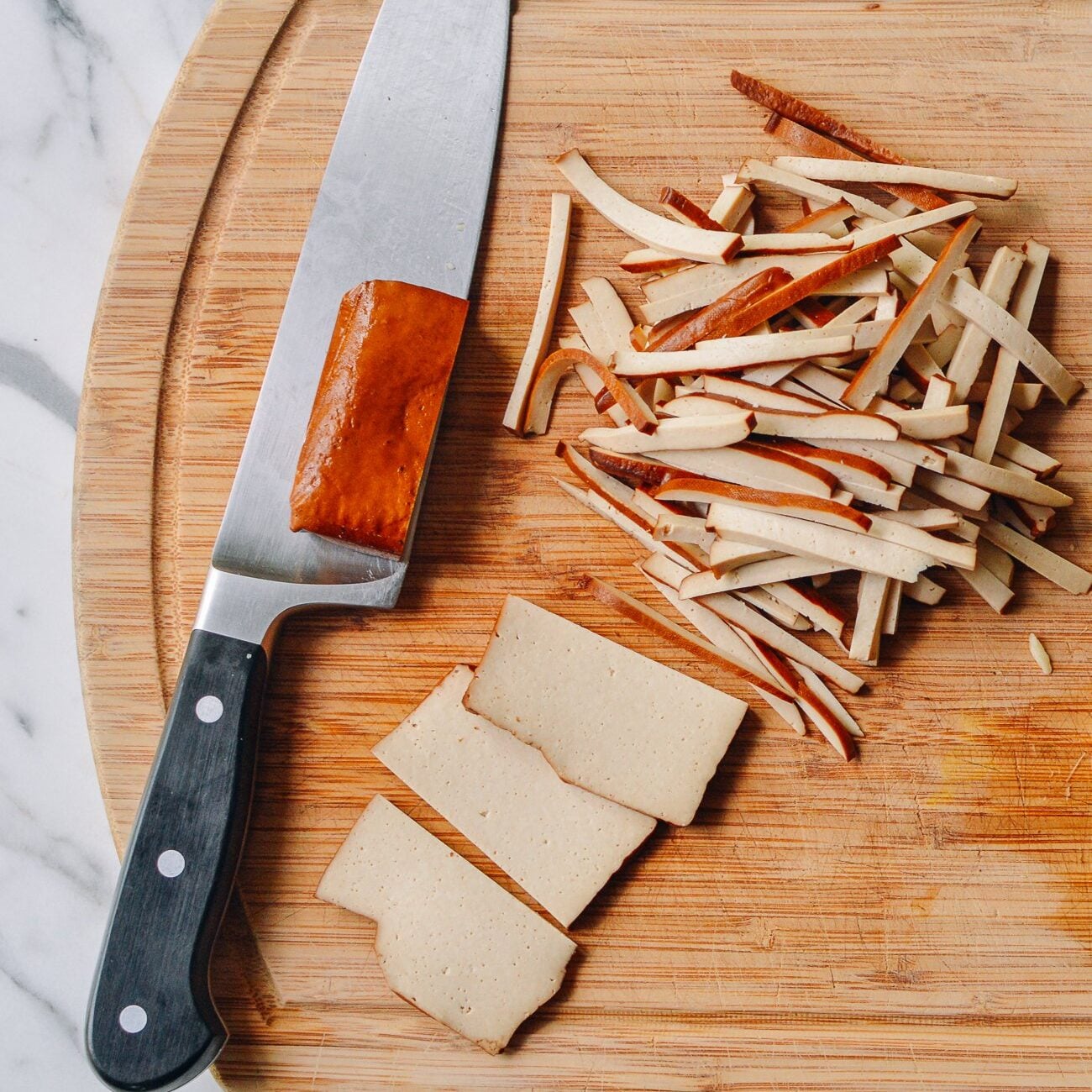 slicing pressed tofu or doufugan on cutting board