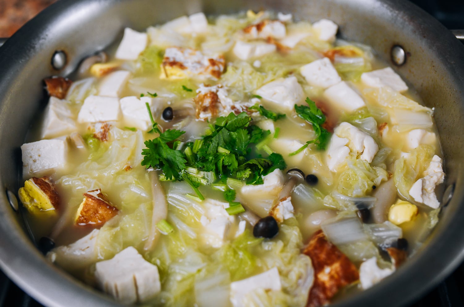 adding cilantro to tofu soup