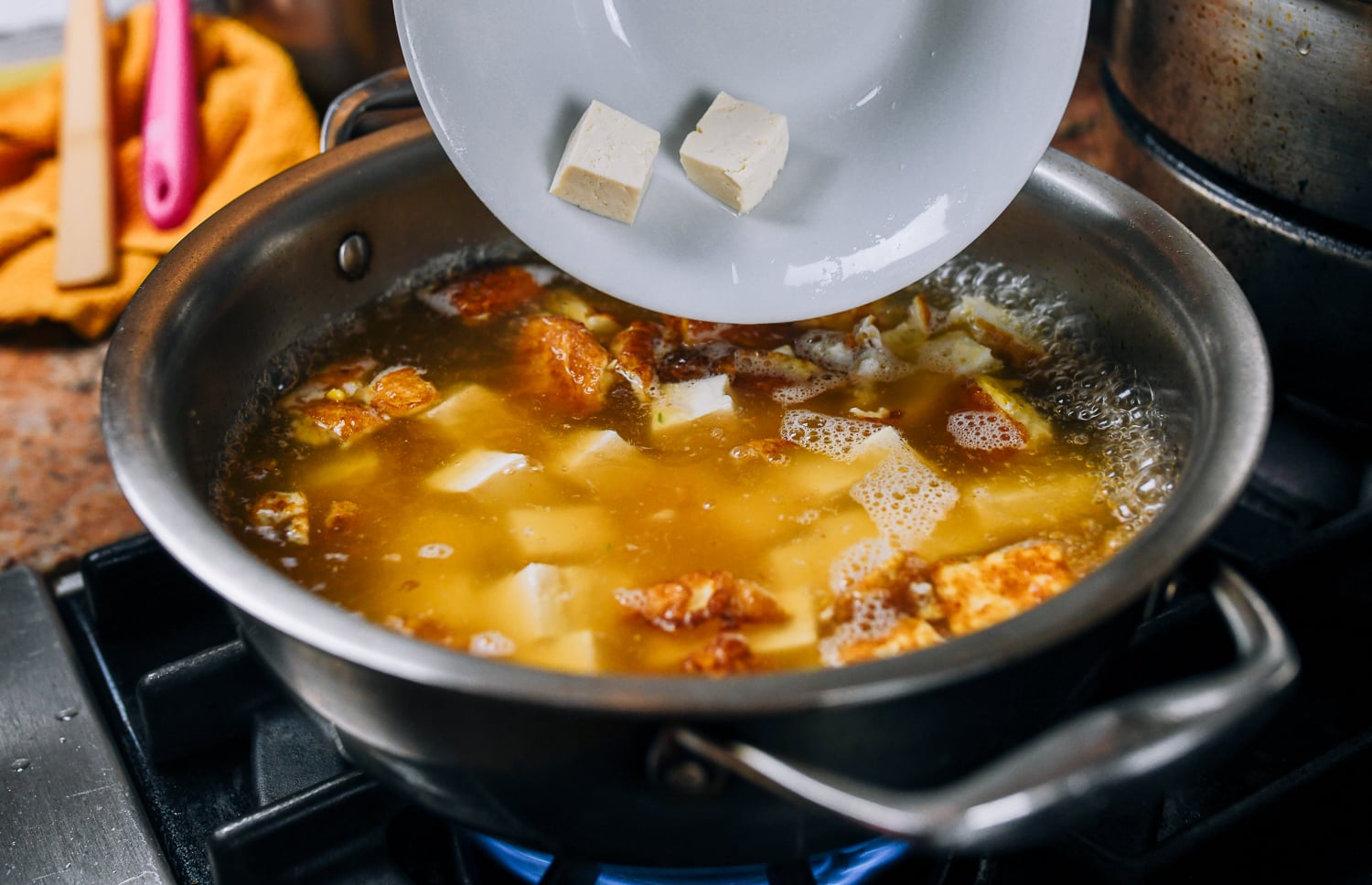 adding tofu to pot of soup