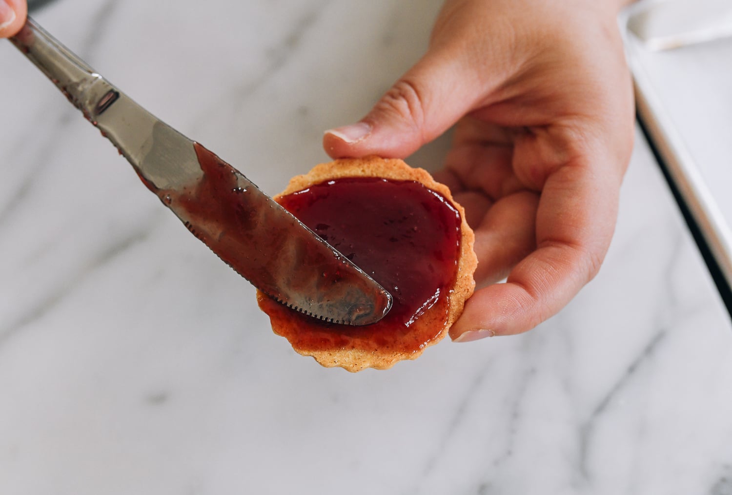 spreading jam on cookie base