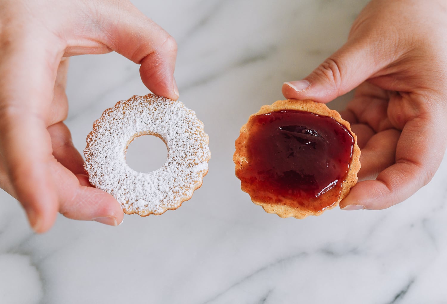 holding jam cookie base and powdered sugar lid for linzer cookies