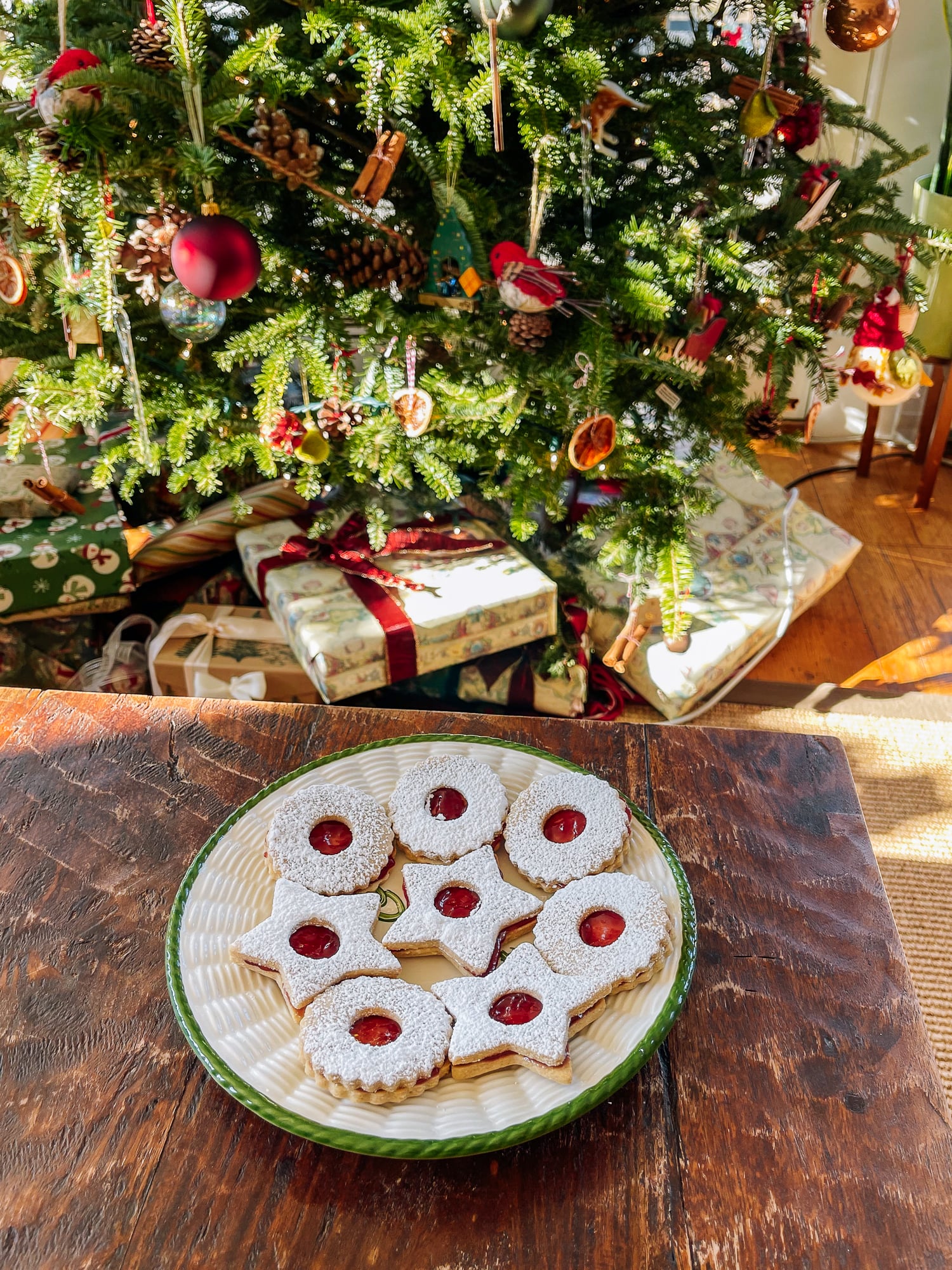 plate of christmas cookies on table in front of christmas tree