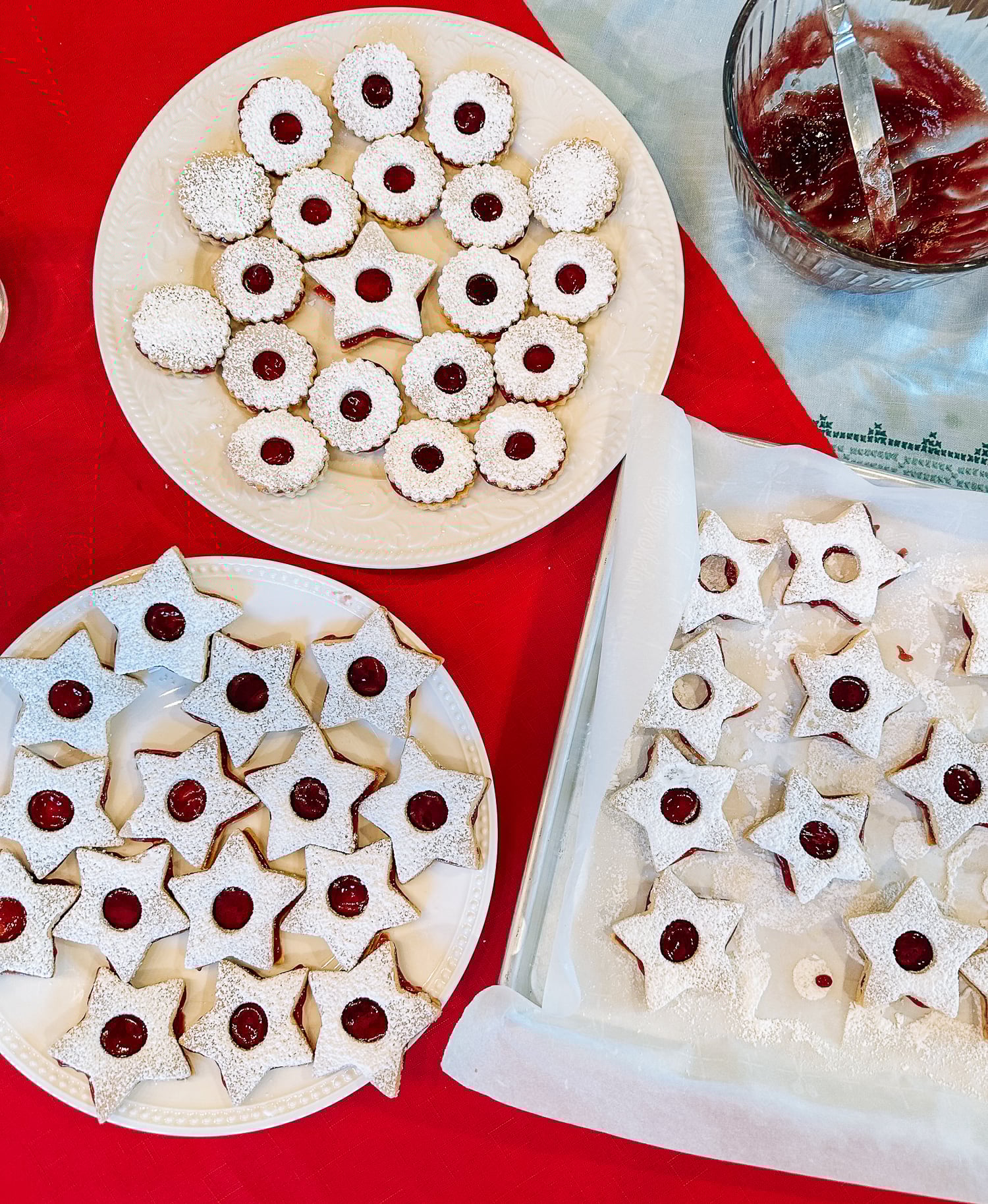 three plates of linzer cookies in star and circle shapes