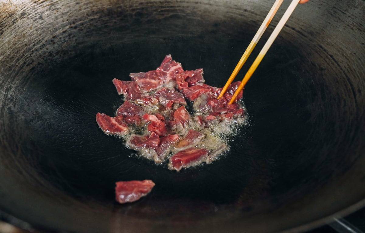 sliced flank steak in oiled wok