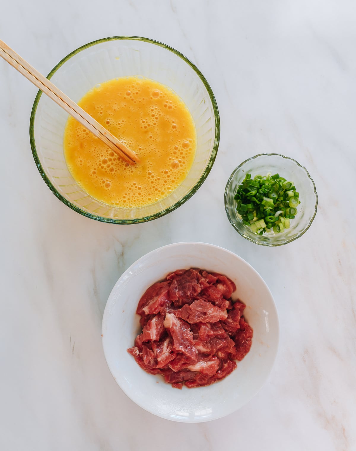 beaten eggs in bowl, chopped scallions, and sliced marinated beef