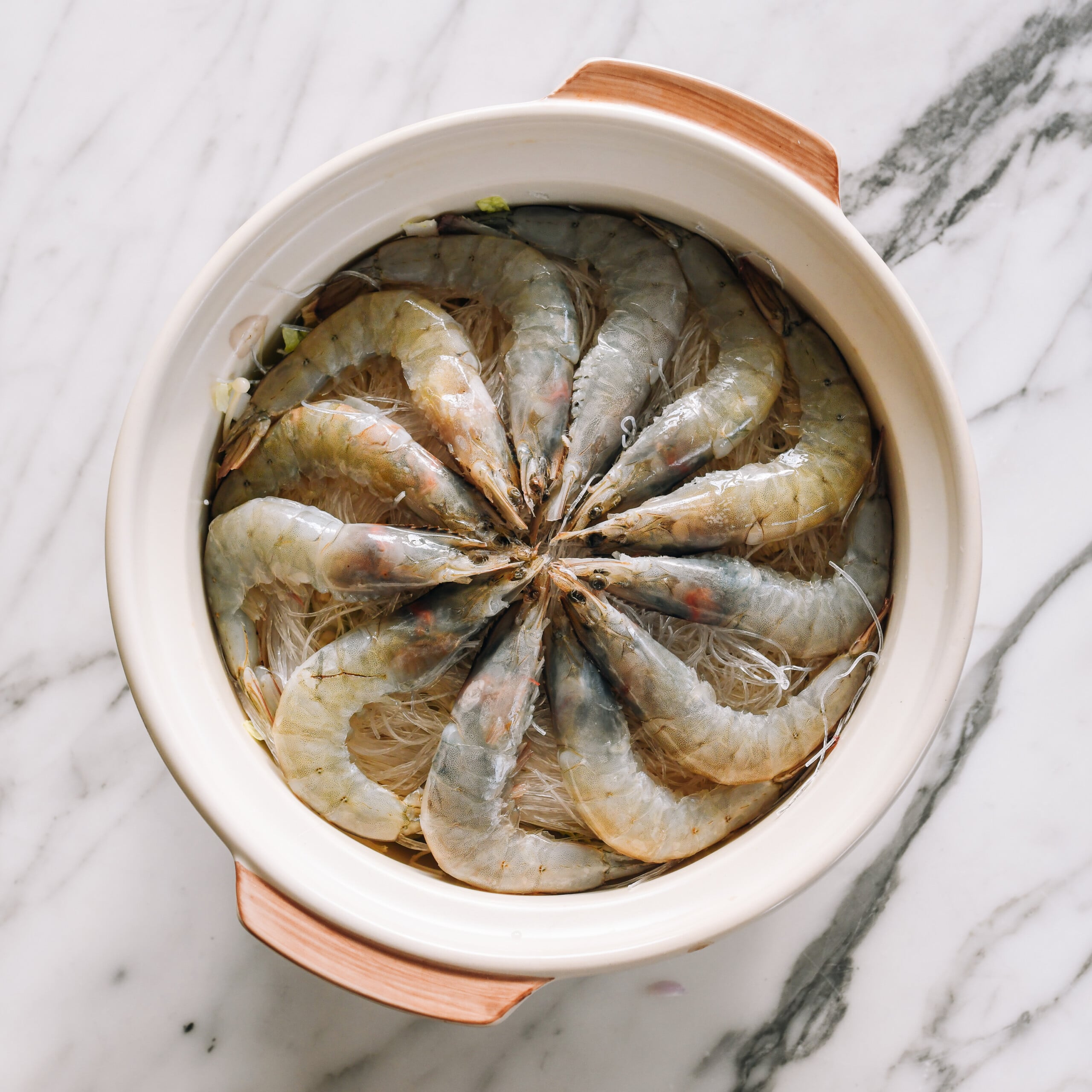 whole shrimp arranged in a circle on top of vegetables and noodles