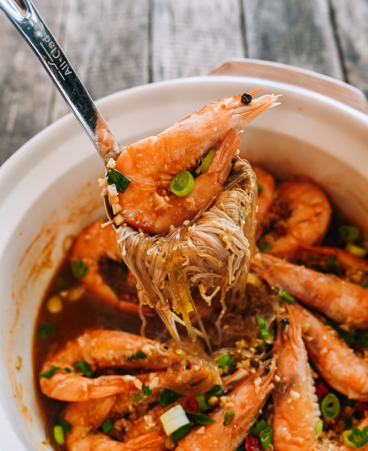 Lifting shrimp, glass noodles, and mushrooms with ladle