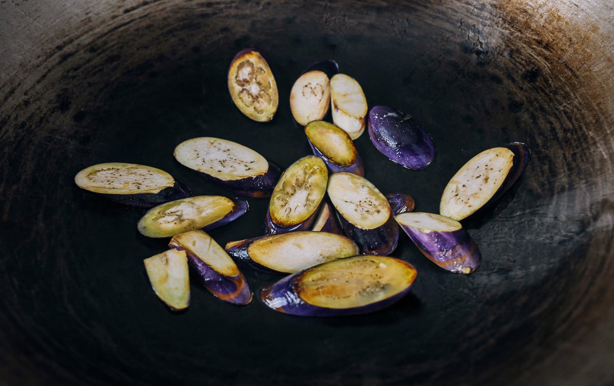 searing Chinese eggplant slices in a wok