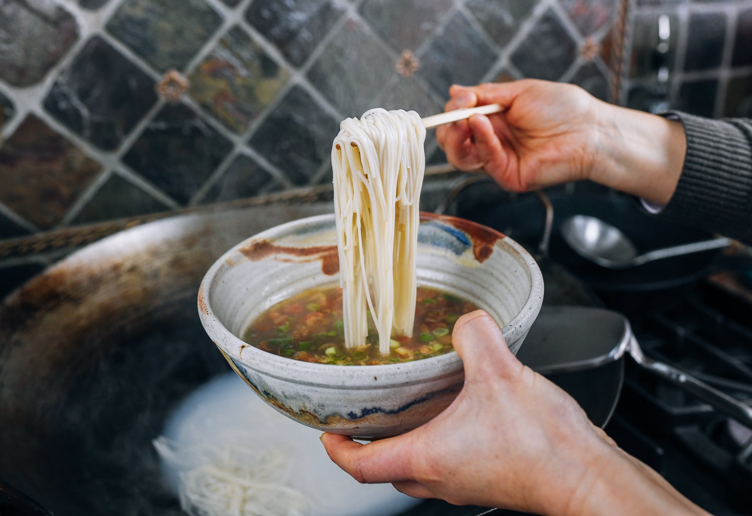 adding noodles to bowl with soup