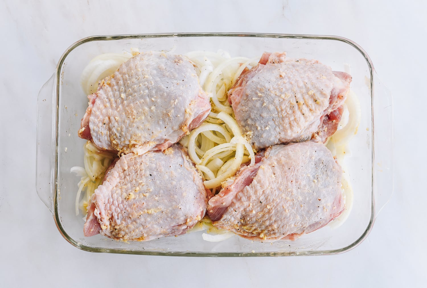 marinated turkey thighs on bed of onions in baking dish