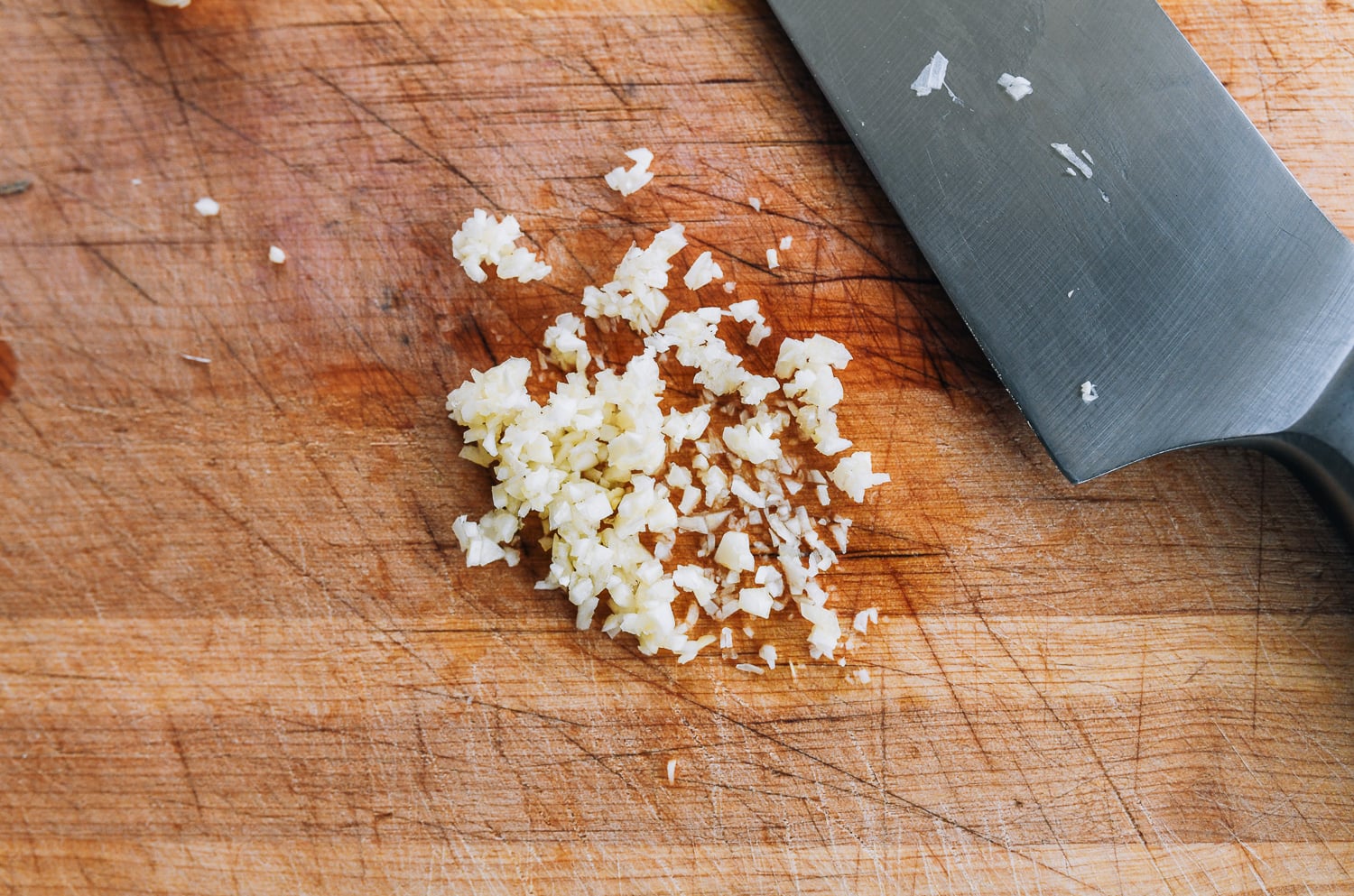 minced garlic on cutting board with knife