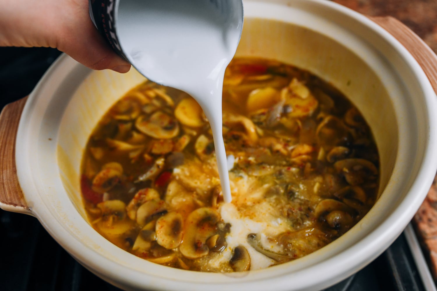 pouring coconut milk into soup
