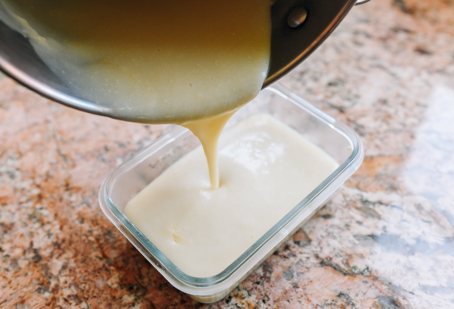 pouring cooked chickpea liquid into rectangular container