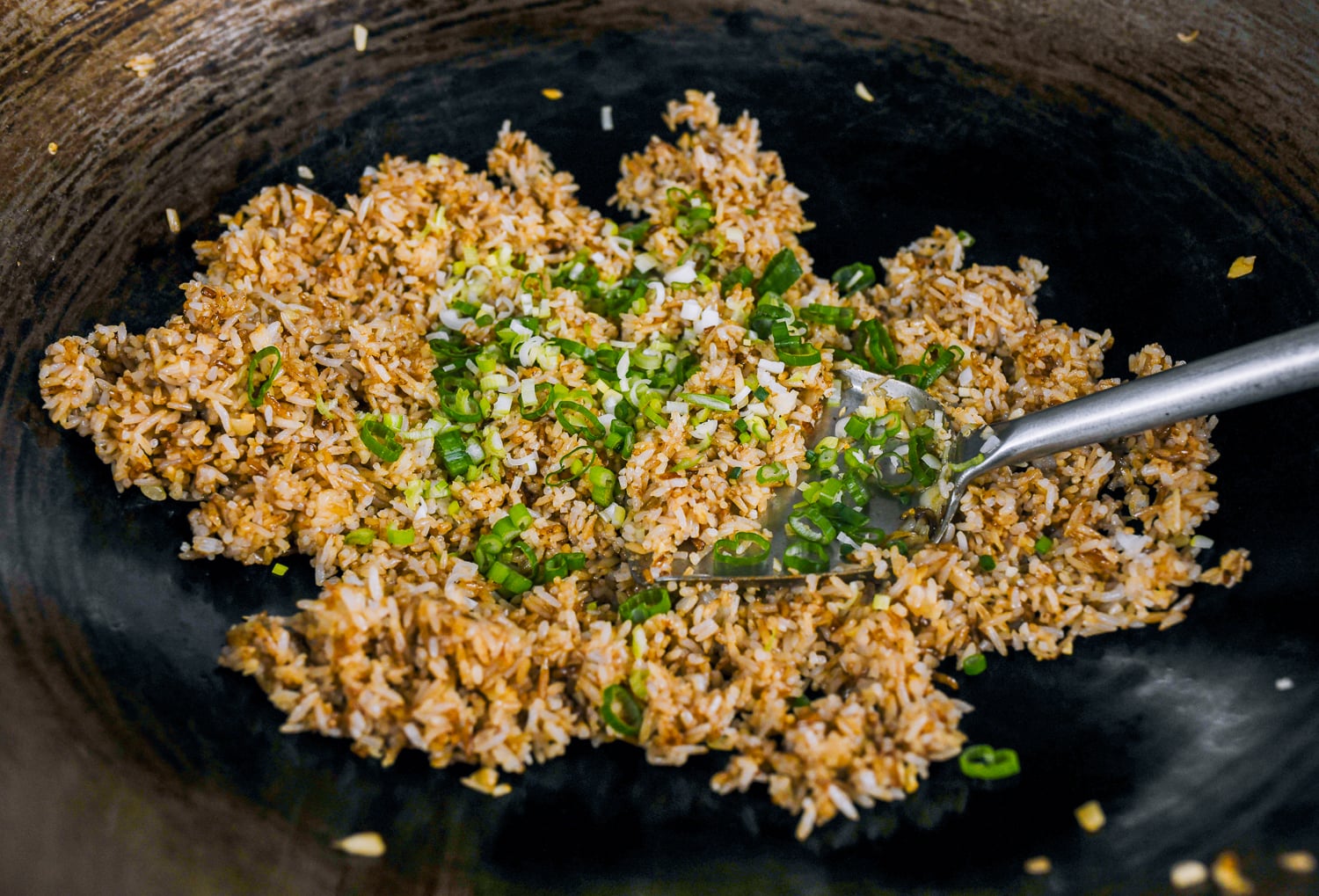 adding chopped scallions to garlic fried rice