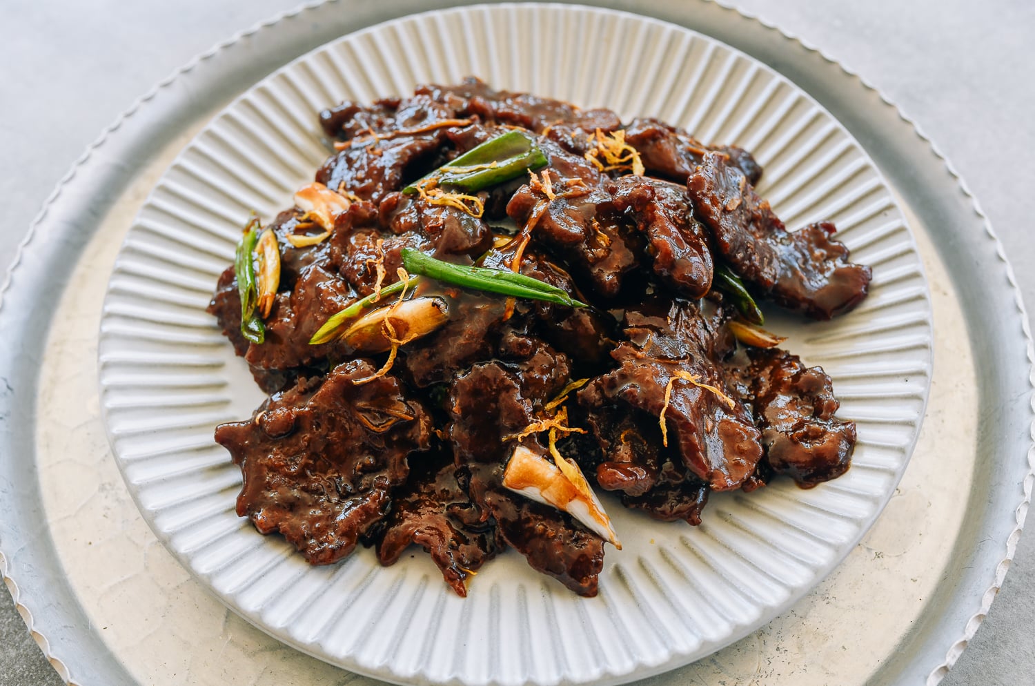 plate of ginger beef garnished with caramelized frizzled ginger