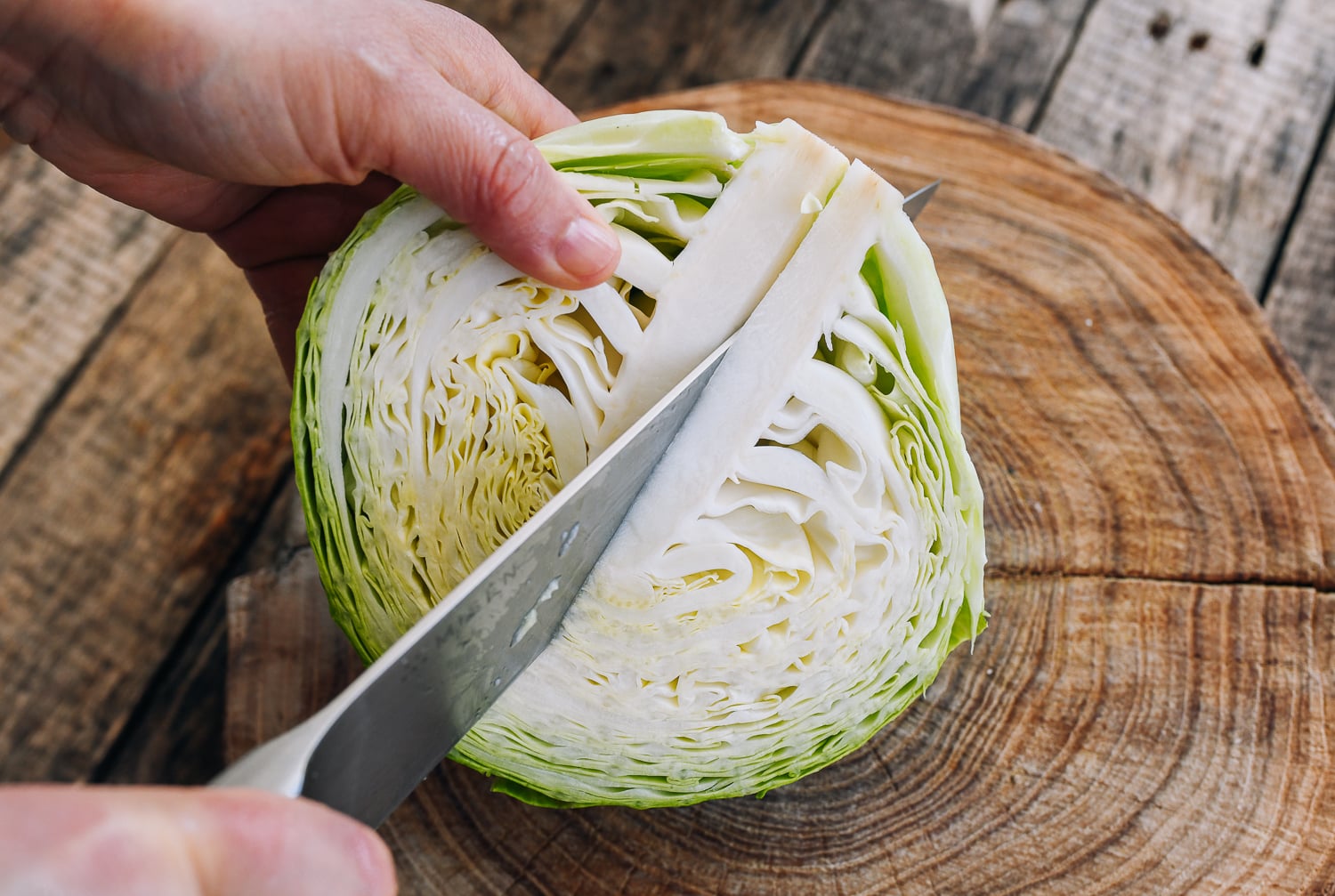 cutting head of green cabbage on cutting board