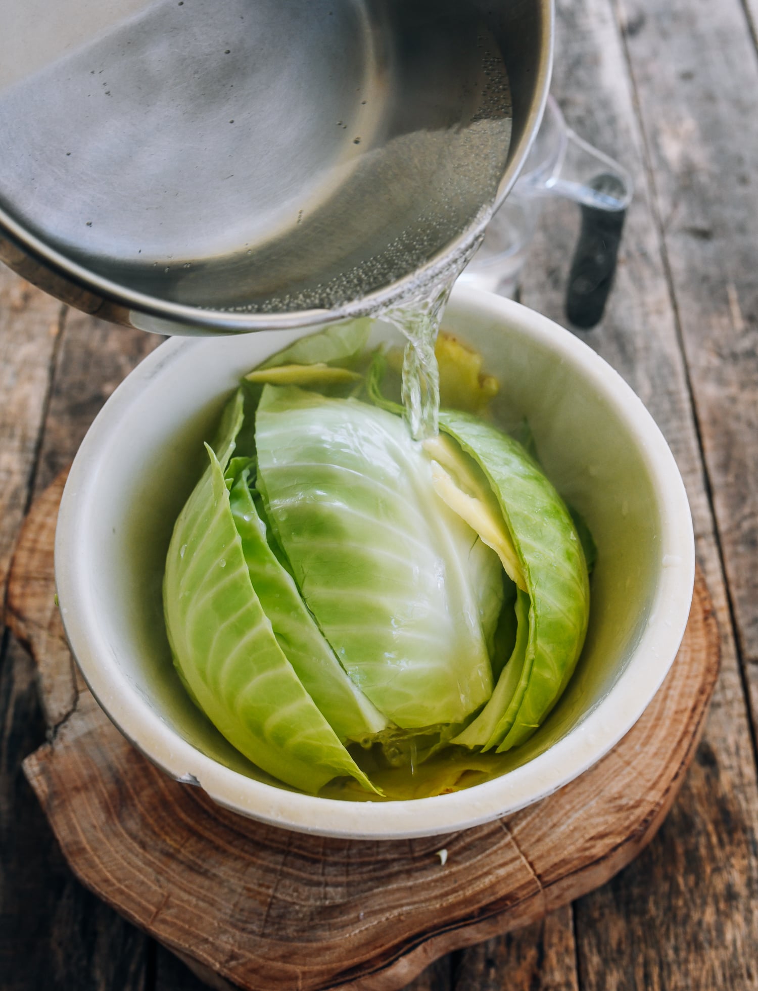 pouring boiling water over cabbage and ginger in bowl