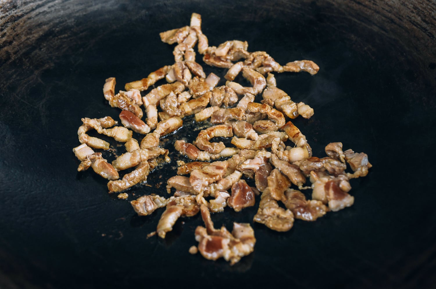 seared strips of pork belly in wok