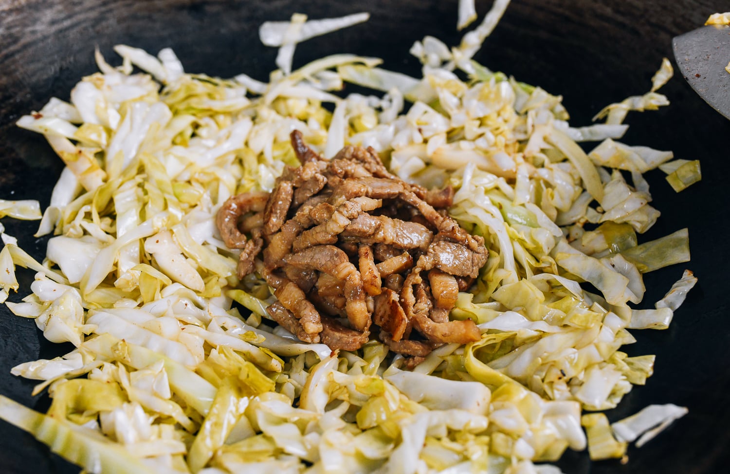 adding pork back to cabbage in the wok