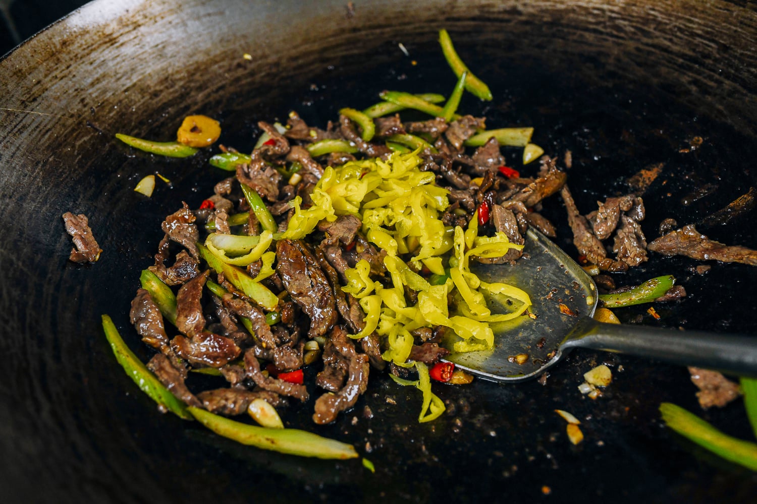 adding pickled peppers to beef and vegetables