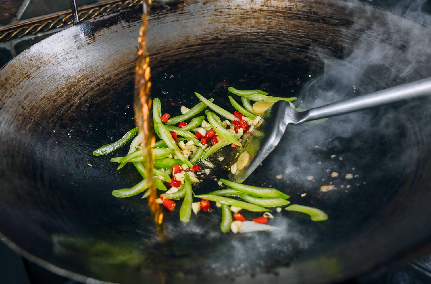 pouring shaoxing wine into wok with chilies and vegetable