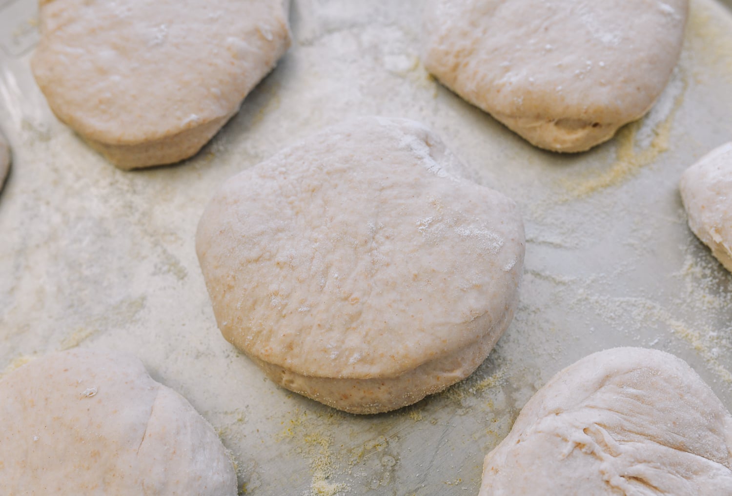 cut english muffin on semolina lined baking sheet