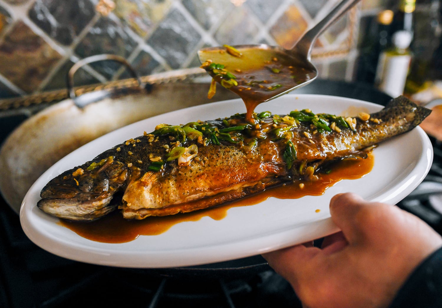 pouring sauce over trout on dish