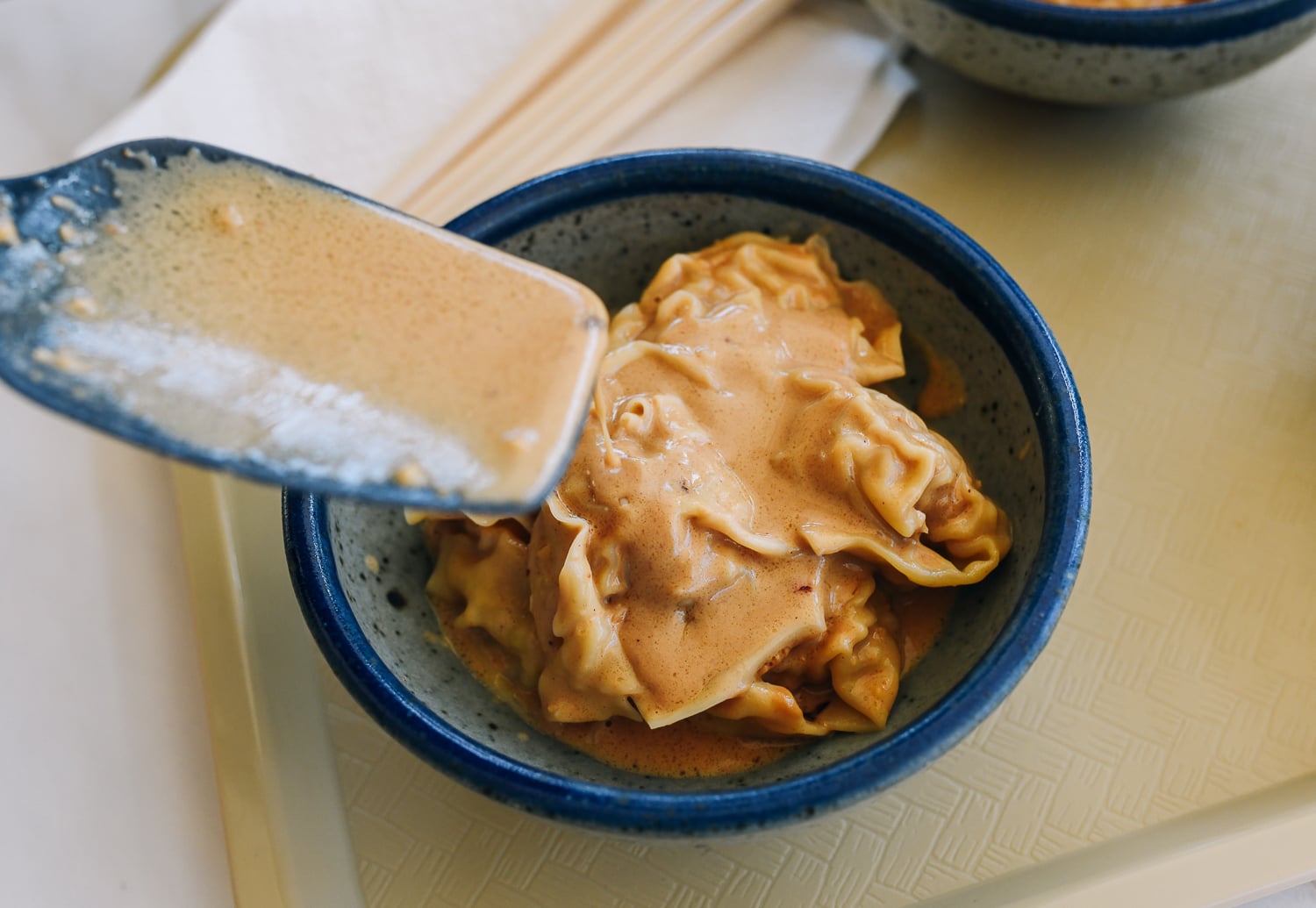 adding peanut sauce to wontons