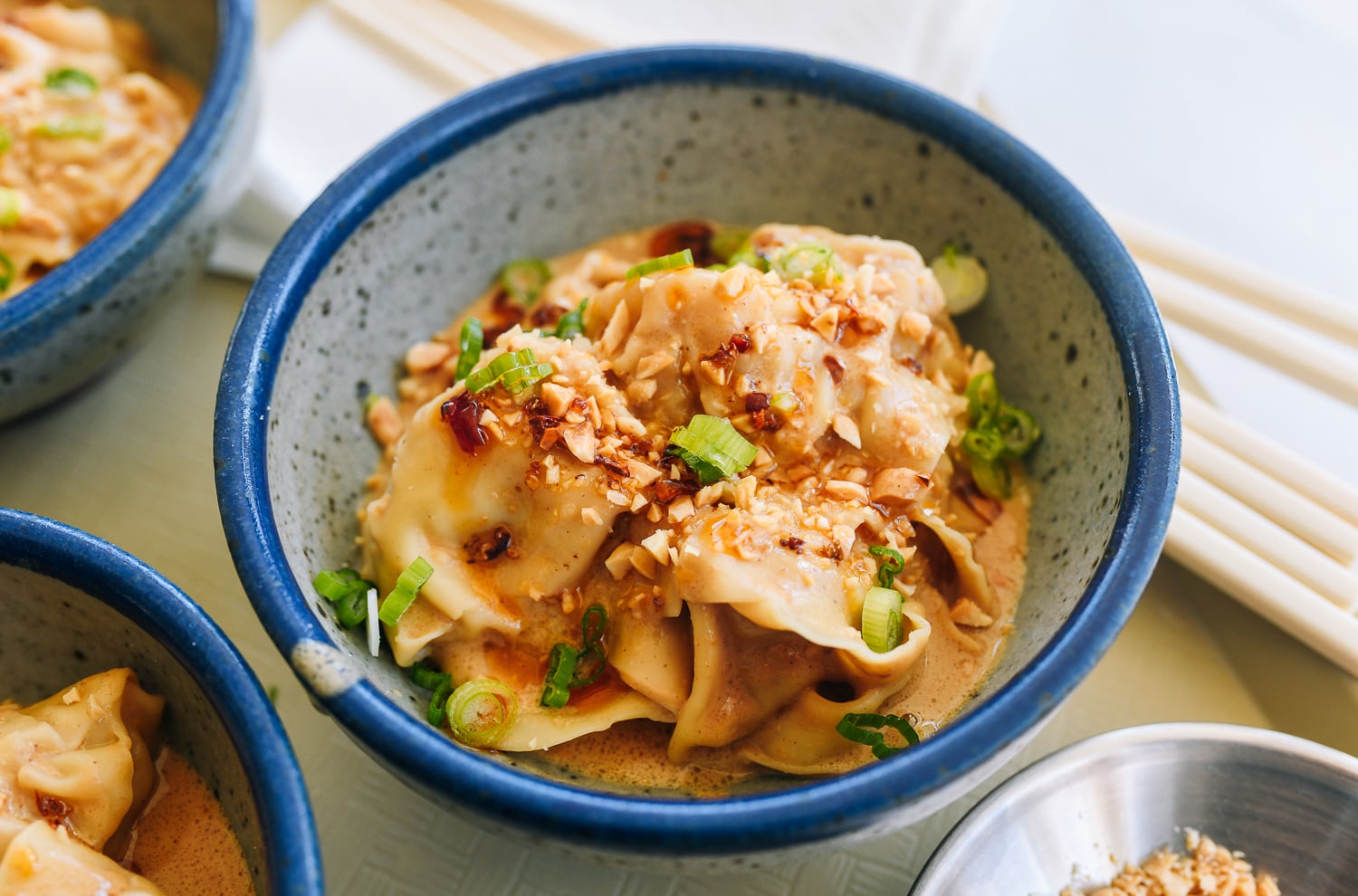 peanut sauce wontons with scallions, chopped peanut, and chili oil