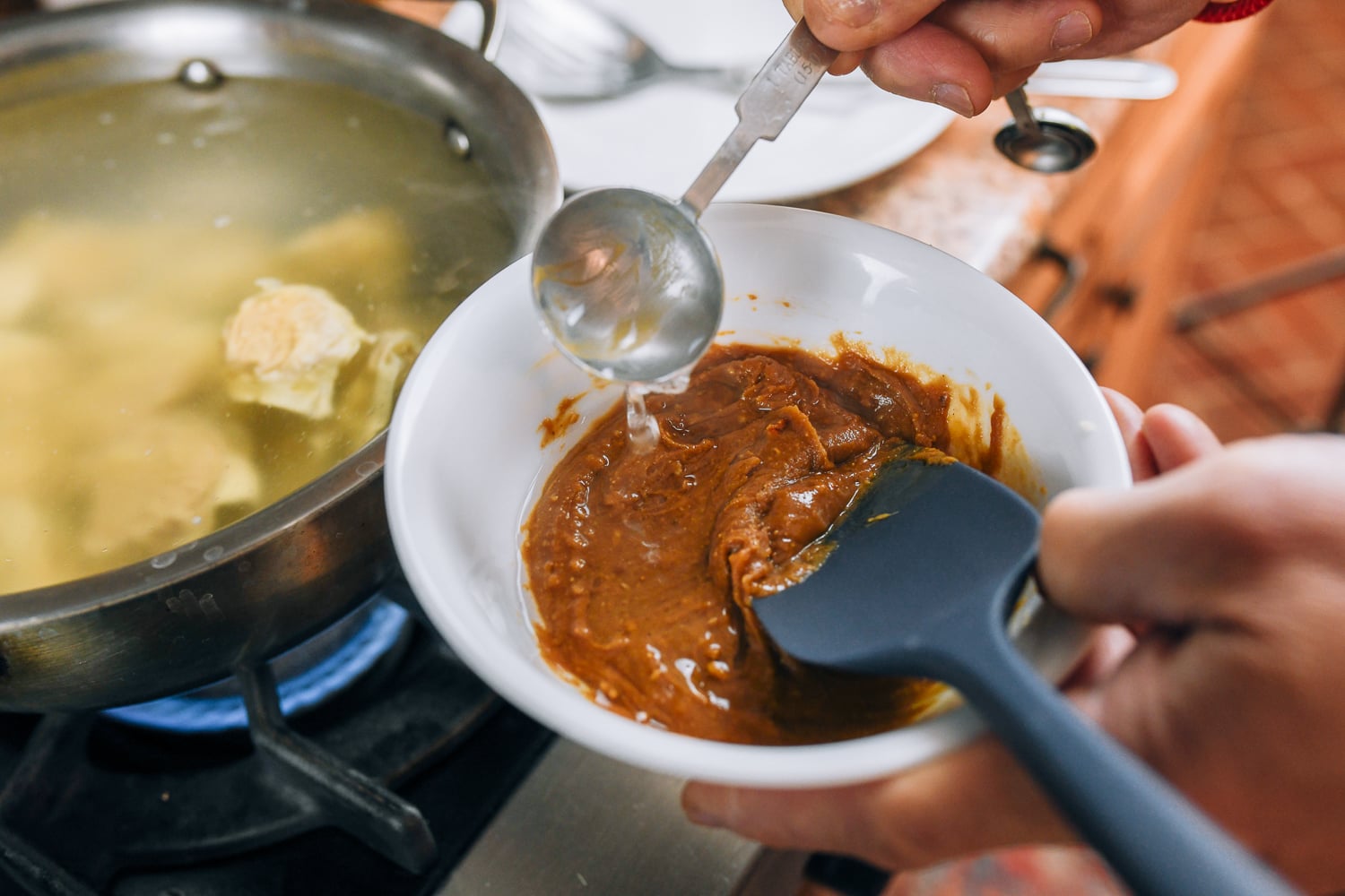 adding hot cooking water to peanut sauce