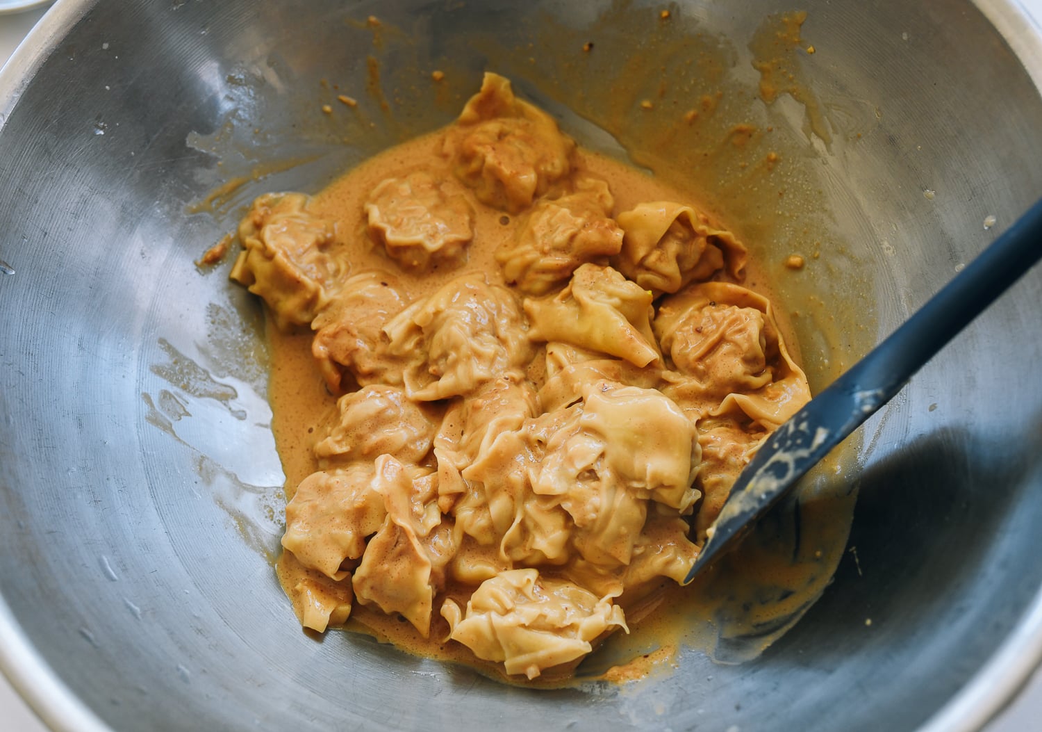 mixing peanut sauce into wontons