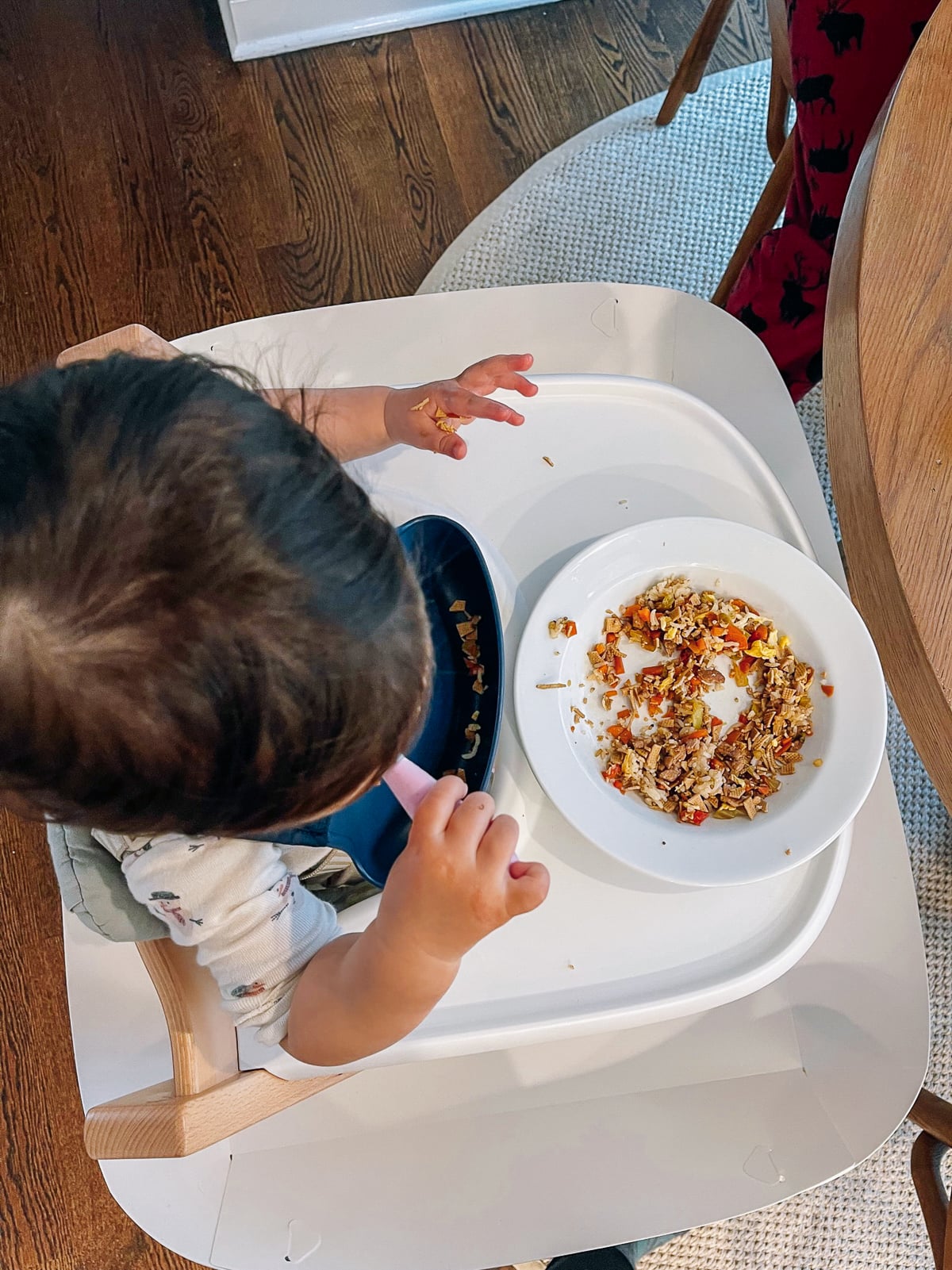 toddler eating vegetables and tofu chopped up with rice