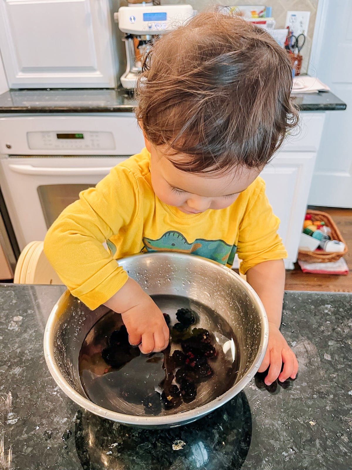 Ethan washing blackberries in metal bowl of water