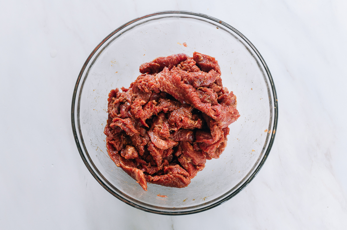 marinated beef flank steak slices in glass bowl