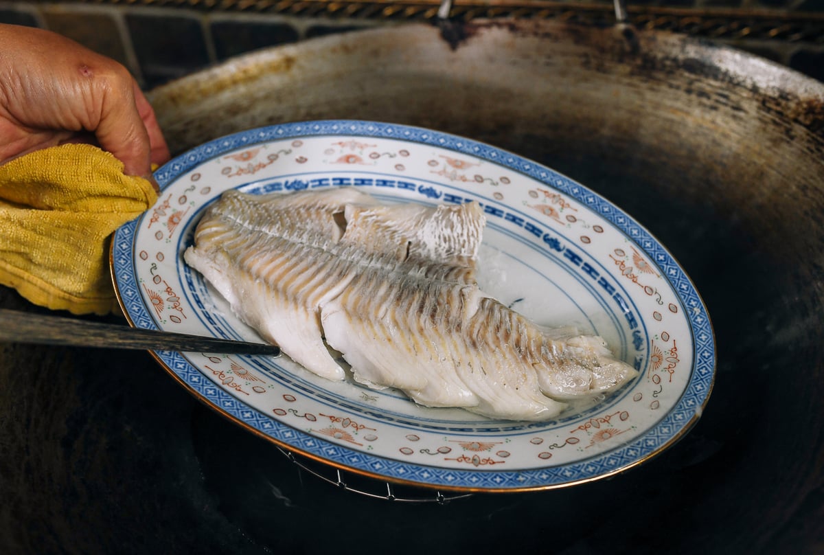 pouring off liquid from plate of steamed cod