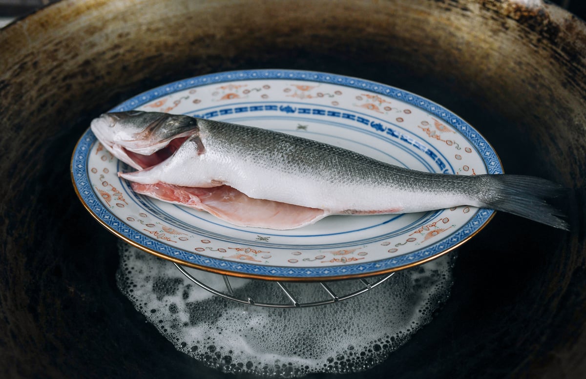 plate with whole fish in wok for steaming