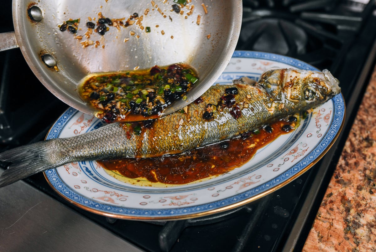 pouring black bean garlic sauce over steamed whole fish