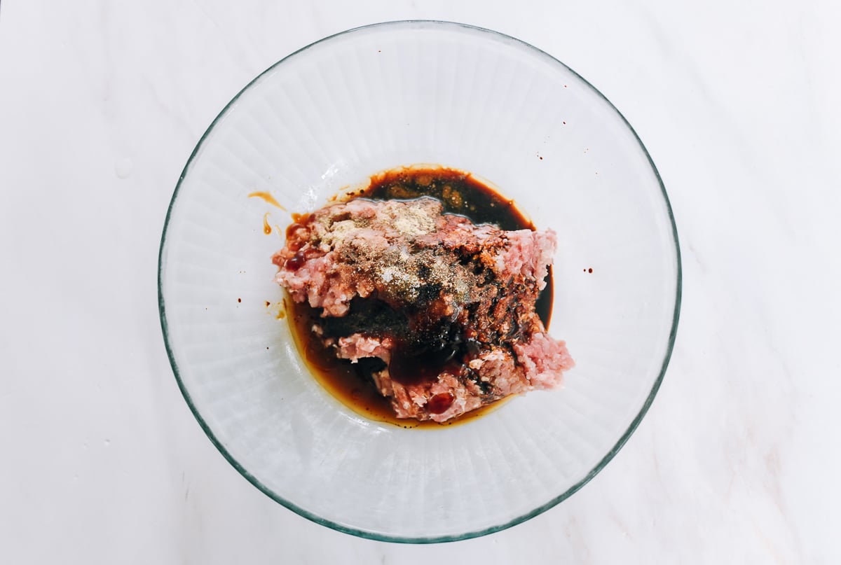 seasoning ingredients added to ground pork in bowl