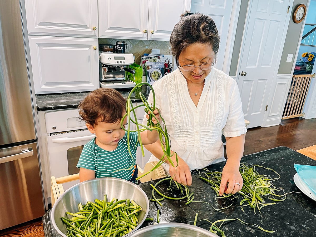 Ethan preparing garlic scapes with Judy