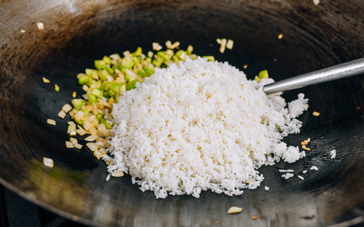 cooked white rice added to vegetables in wok