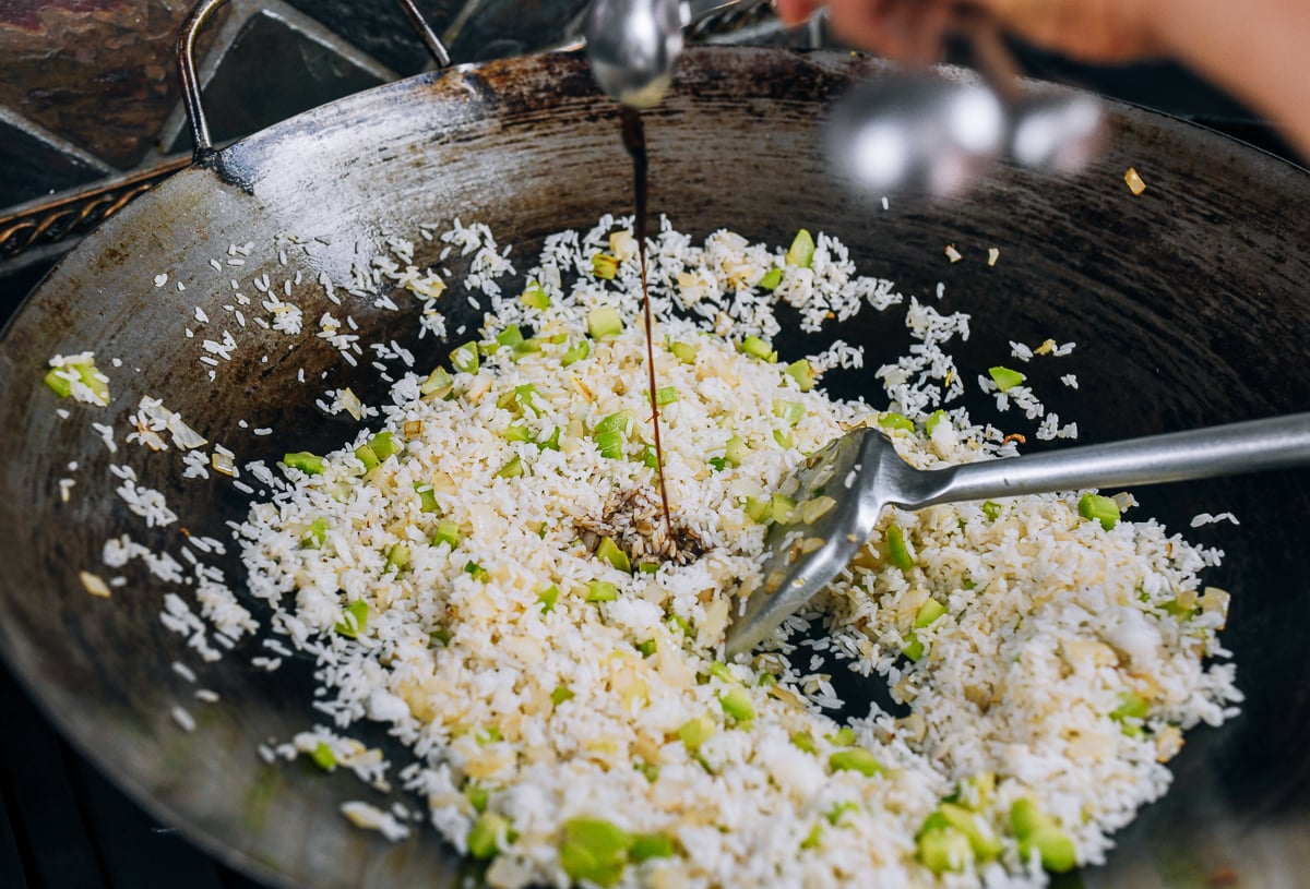 seasoning rice in wok with soy sauce
