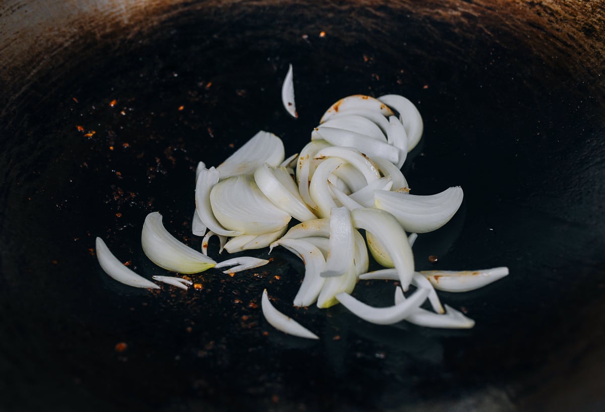 Adding sliced onions to wok